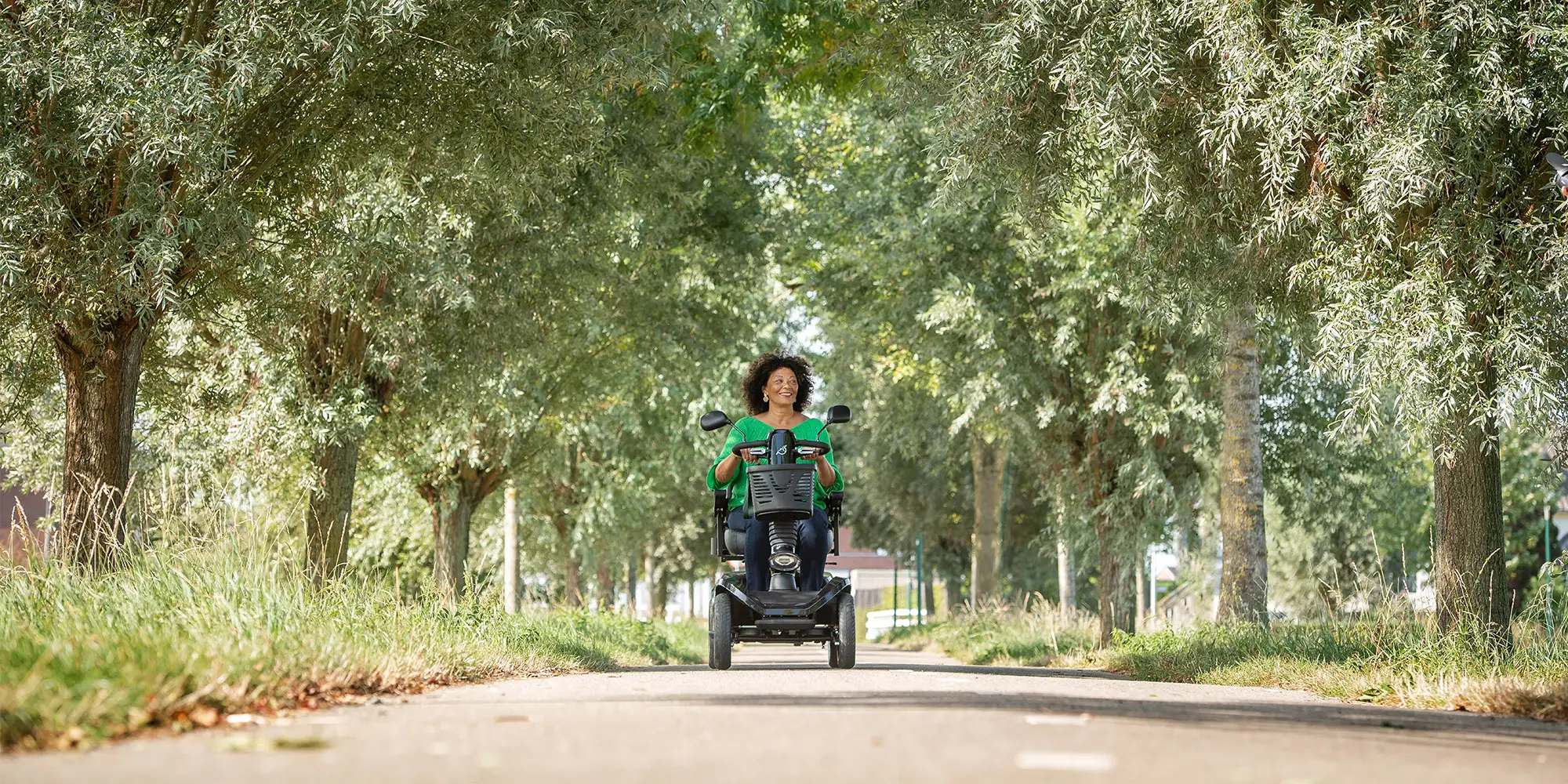 Vrouw rijdt met haar scootmobiel over straat.
